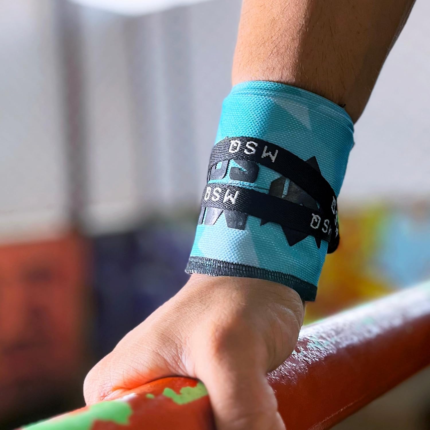 Close-up of a hand gripping a pull-up bar, wearing Gripzora Blue Streak calisthenics wrist wraps for enhanced stability and injury prevention.