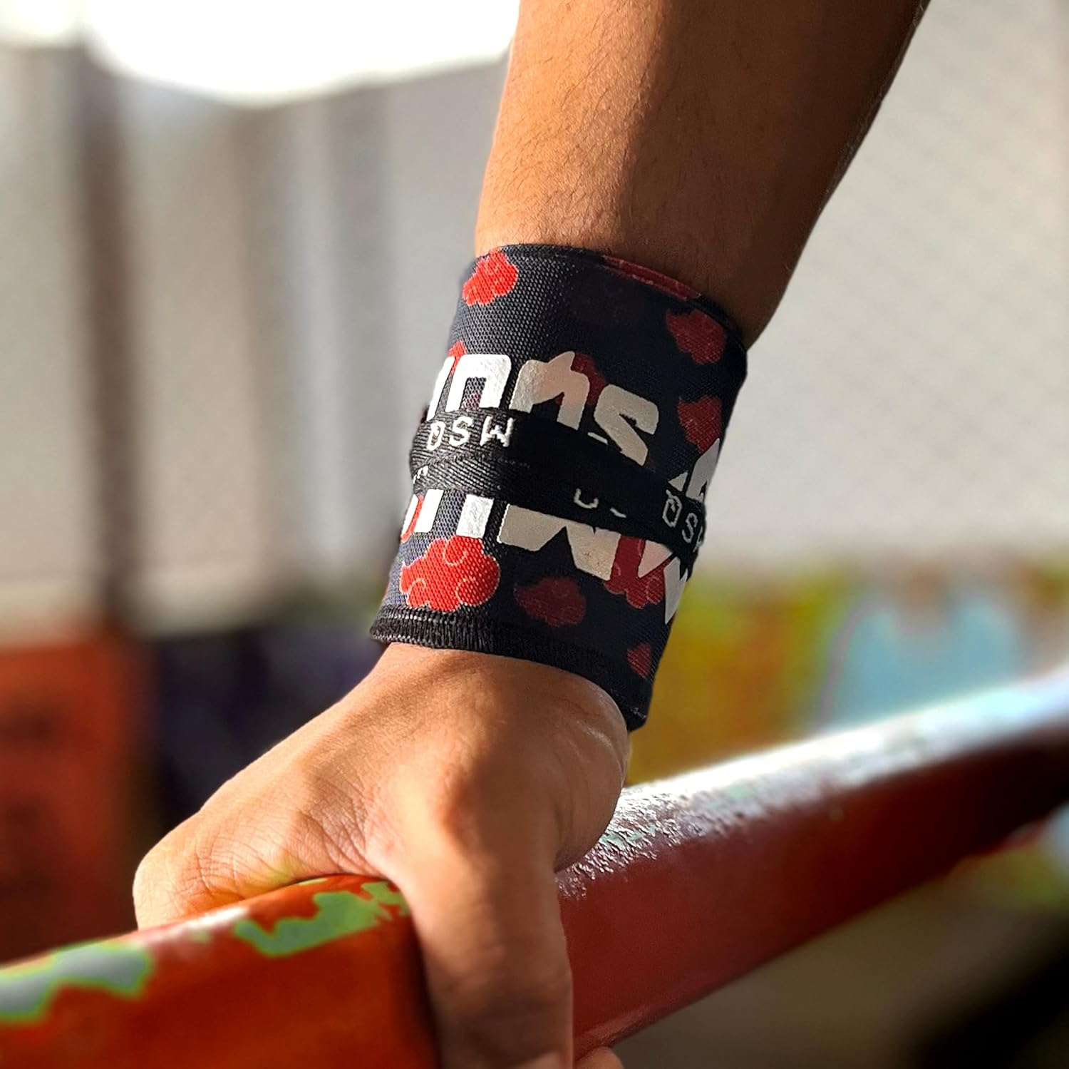 Close-up of a hand gripping a pull-up bar, wearing Gripzora Crimson Cloud calisthenics wrist wraps for enhanced stability and injury prevention.