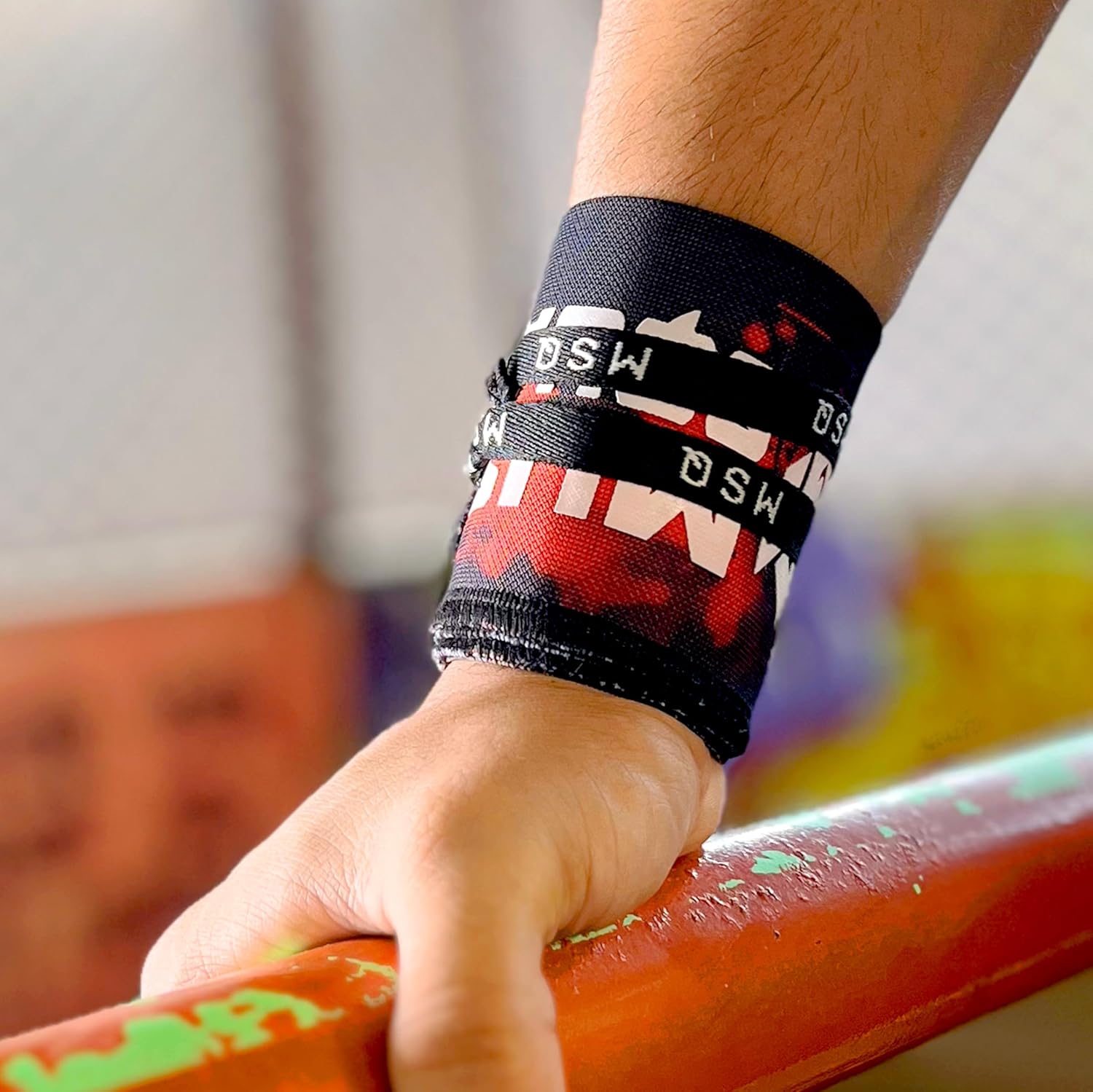 Close-up of a hand wearing Gripzora Crimson Wave wrist wraps, providing crucial stability and support during heavy lifts and calisthenics training.