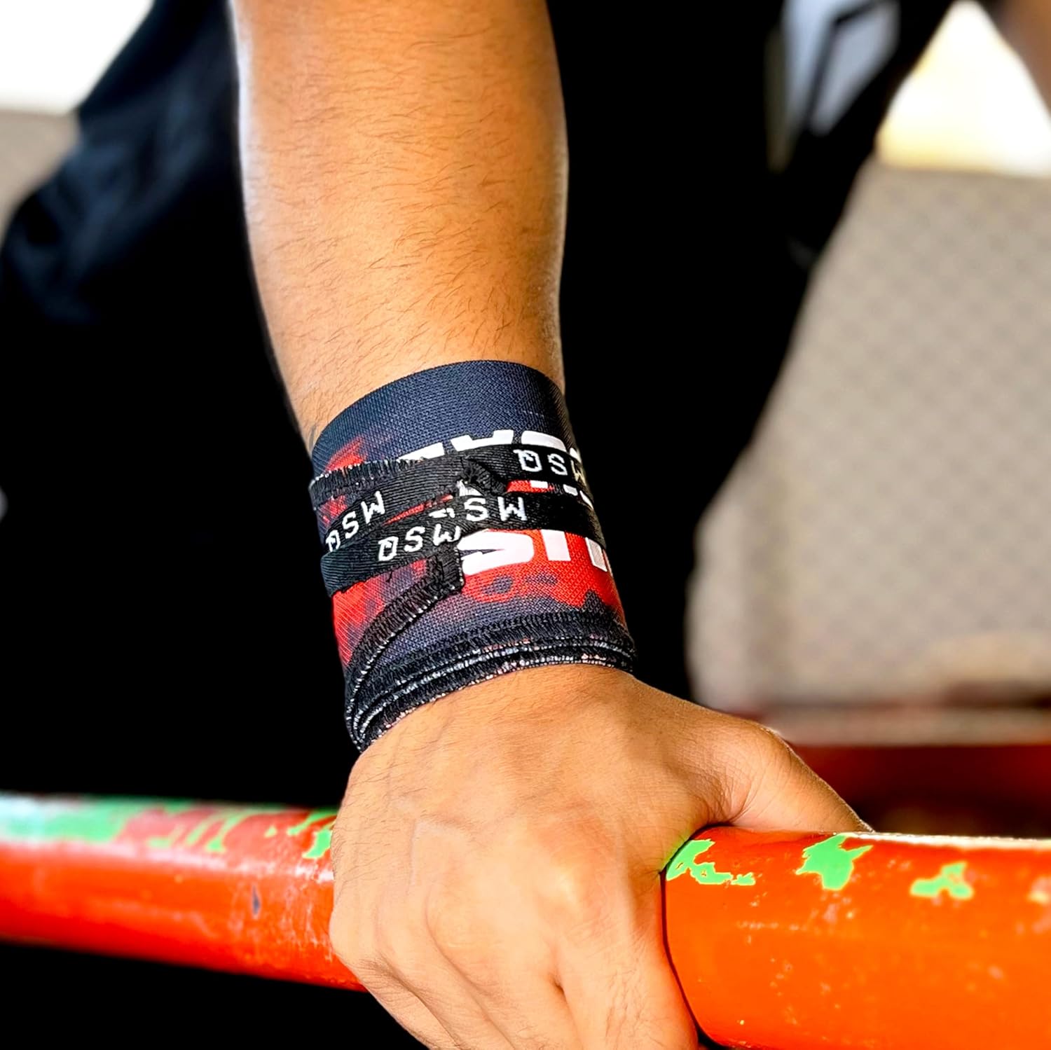 Close-up of a hand gripping a pull-up bar, wearing Gripzora Crimson Wave calisthenics wrist wraps for enhanced stability and injury prevention.